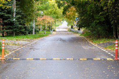 Asfalt yol banliyödeki mesafeye doğru çekiliyor. Ön planda trafik emniyet şeridi var. Seçici odak