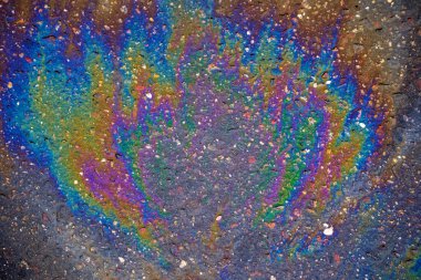 Islak asfaltta yakıt lekesi. Yoldaki benzin sızıntısının renkli lekeleri..