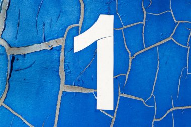 Kırık mavi arka planda bir numara. 1 numaralı eski plaket. Yakın plan. Seçici odak.