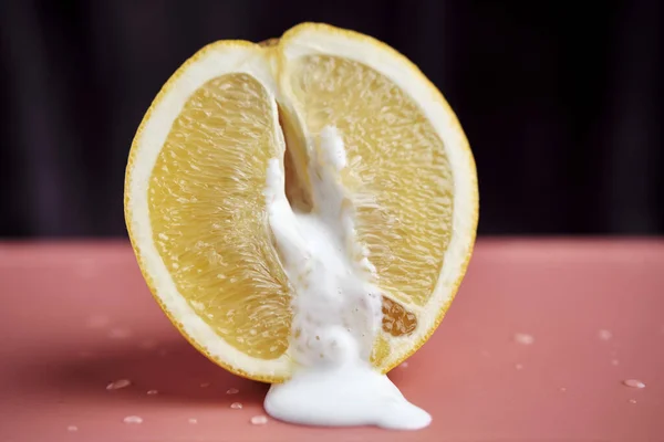 Half an orange and the resulting yogurt. Erotic concept. A symbolic image of a vagina and sperm. Unprotected sex. Close-up. Selective focus