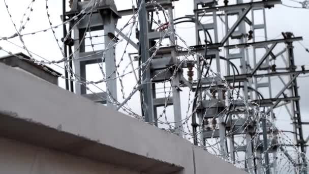 高電圧塔の背景にコンクリートフェンスの上に鉄条網 — ストック動画
