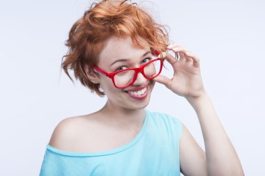 Kızıl saçlı kız mavi bluz ve kırmızı gözlük lens gülümseyen güzel ve sağlıklı bir gülümseme geniş bembeyaz olmadan