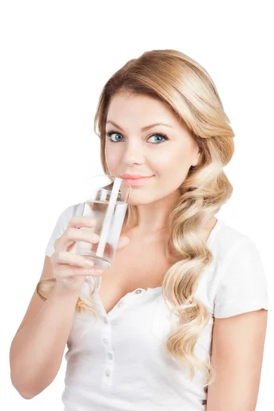 Una mujer joven y guapa en T-short blanco sostiene un vaso de agua. Hermosa rubia de pelo largo chica está bebiendo agua de vidrio en blanco. Captura de estudio . — Foto de Stock