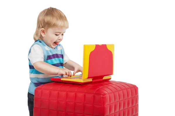 Happy 2 roky dítěte s počítačem. mladý technik. malý chlapec pomocí červené a žluté přenosný počítač s jeho jazykem na bílém pozadí. Studio záběr — Stock fotografie