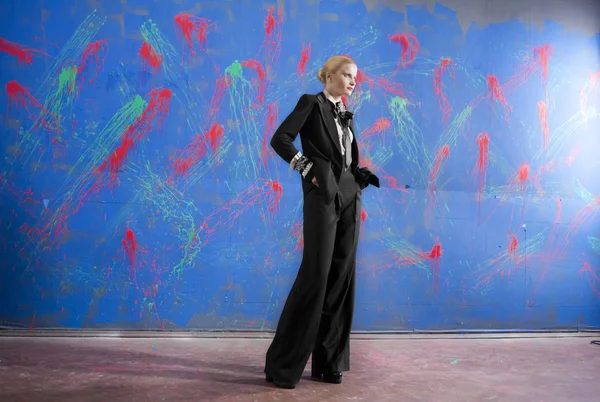 Unga blonda kvinnan i en snygg kostym mot grunge vägg — Stockfoto