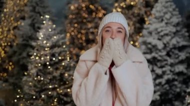 Sihirli ormanda kar yağıyor. Güzel sarışın kadın öpücükler saçıyor. Havada aşk kokusu var. olumlu dostça duygular ve duygular. Video görüntüleri. Şık şapka ve eldivenler, kırmızı kazak. tatil havası
