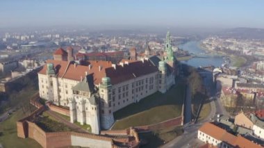 Drone kamera Wawel Hill 'deki kalenin altından yukarı hareket ediyor. Yoğun şehir Krakow Polonya' nın sabah sisi panoramik görüntüsü. Havadan çekilmiş görüntüler. Güzel Visla nehri ve Grunwaldzki köprüsü