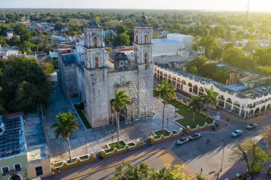 Valladolid Mexico 'daki İglesia De San Servacio Katedrali' nin şehir meydanındaki hava fotoğrafı. Akşam güneşi ışığı. sabit kamera bir yerde. Dekoratif bayraklar dalgalanıyor. Taksi trafiği