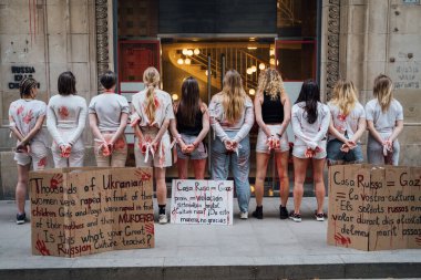28.04.2022 Barselona, İspanya. Rusya 'nın evi. Ukraynalı aktivistlerin Ukrayna 'daki savaş sırasında kadınlara ve çocuklara tecavüz etmelerini protesto etmek. Kanlı ellerde kızlar şiddet kurbanlarını taklit ediyorlar.
