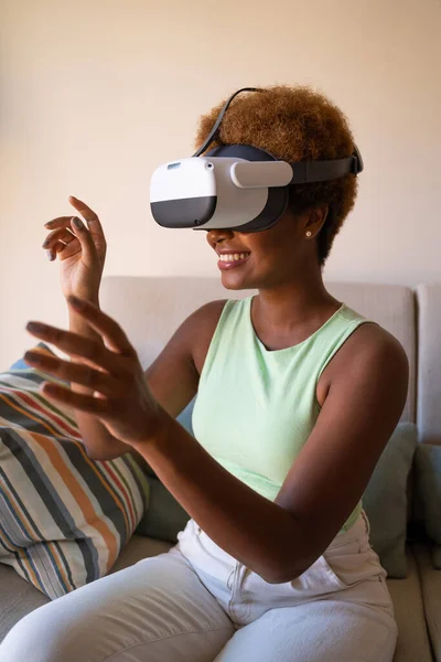 Black skin woman playing VR game at home, copy space. Exited using vr glasses, watching 360 degree video  with virtual reality headset looking up. Vertical composition