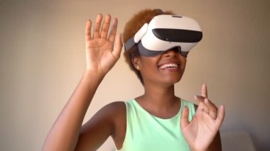Amazed Black woman testing wearing virtual reality simulator headset home. Happy smiling wow positive emotions. Video footage. 
