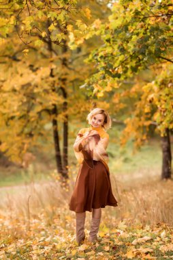 Sonbahar parkında sarı yapraklı yaşlı bir kadın...