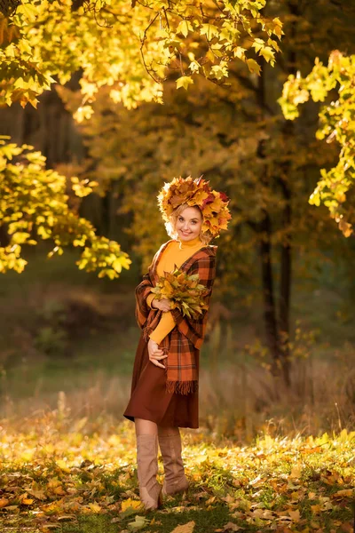 Happy old age. Cheerful elderly woman with yellow autumn leaves in her hands, walking in the park.