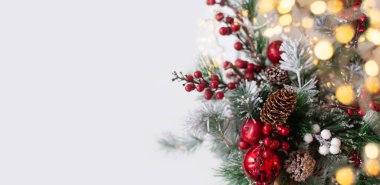 Güzel bir Noel geçmişi. Beyaz arka planda kırmızı süslemeli ladin dalları.