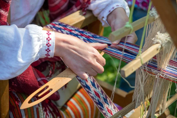 Mujer trabajando en el telar de tejer. Artesanía étnica tradicional del Báltico . Fotos de stock