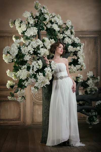 Sposa sorridente vicino all'albero con fiori bianchi . — Foto Stock