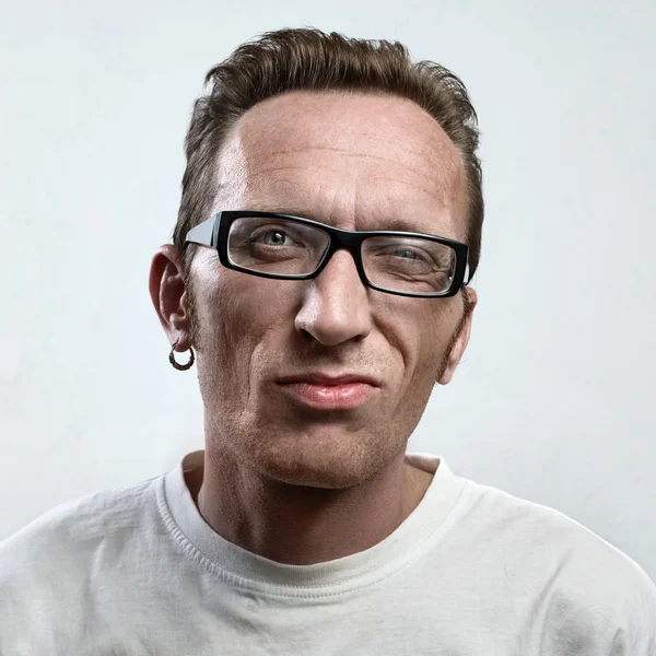 Portrait unsatisfied man with an earring in a white t-shirt on light gray background. face close up. — Stock Photo, Image