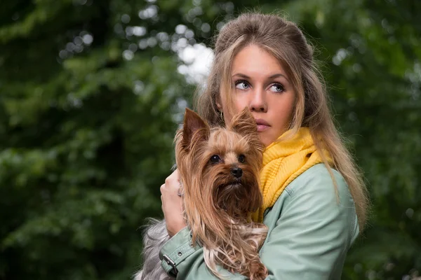 Joven mujer rubia bonita triste en el parque de la ciudad con su perro — Foto de Stock