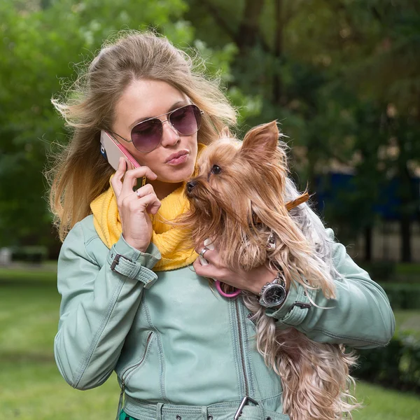 Chica hablando de teléfono celular y besando a su perro — Foto de Stock