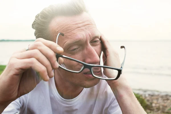 Homem esfregar os olhos cansados na praia após o dia de trabalho duro . — Fotografia de Stock