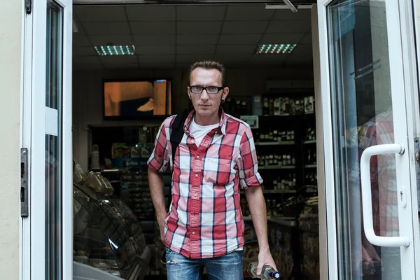 Young man bought a bottle of vodka in alcohol shop — Stock Photo, Image