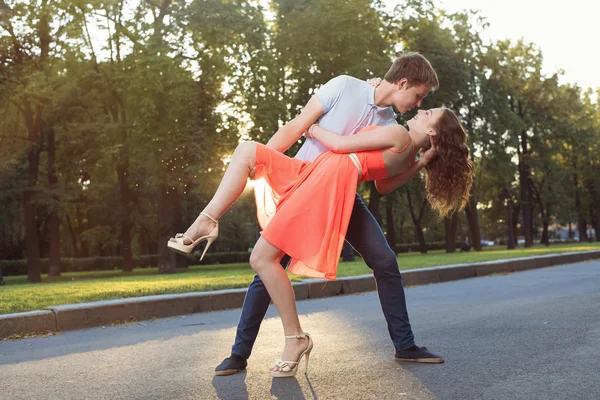 Feliz joven pareja enamorada bailando en la luz del atardecer en la calle — Foto de Stock