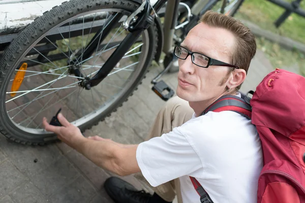 Man pump up the bike wheel outdoor on the city street — Stock Photo, Image