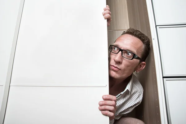 Rémült ember bekukucskál, fehér szekrény — Stock Fotó