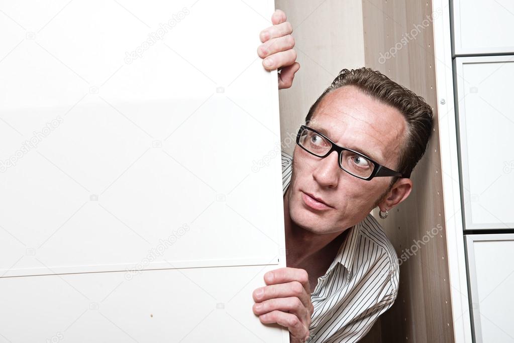 Surprised man inside white wardrobe