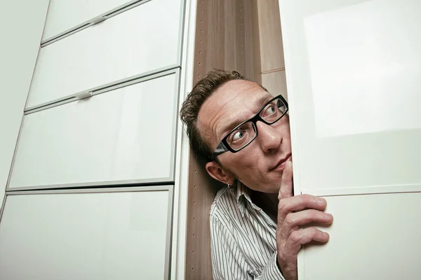 Frightened man peep out white wardrobe. Copy space right — Stock Photo, Image