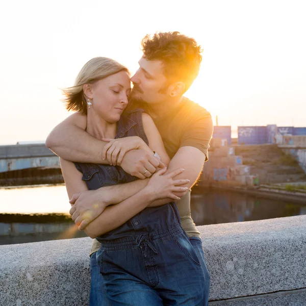 Счастливая молодая пара обнимается в лучах заката — стоковое фото