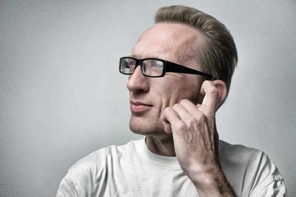 A pensar num homem de fundo cinzento texturizado. Retrato de close-up de um homem de negócios casual jovem e pensativo olhando para o espaço de cópia e coçar a orelha . — Fotografia de Stock