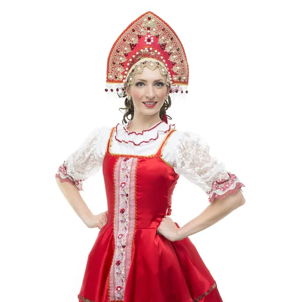 Glimlach jonge vrouw handen op de heupen portret in Russische traditionele kostuum--rode sarafan en kokoshnik. — Stockfoto