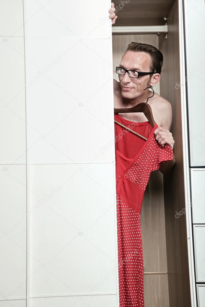 Curious naked man in eyeglasses looking out from white wardrobe