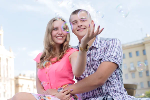 Young happy couple catching soap bubbles — Stock Photo, Image