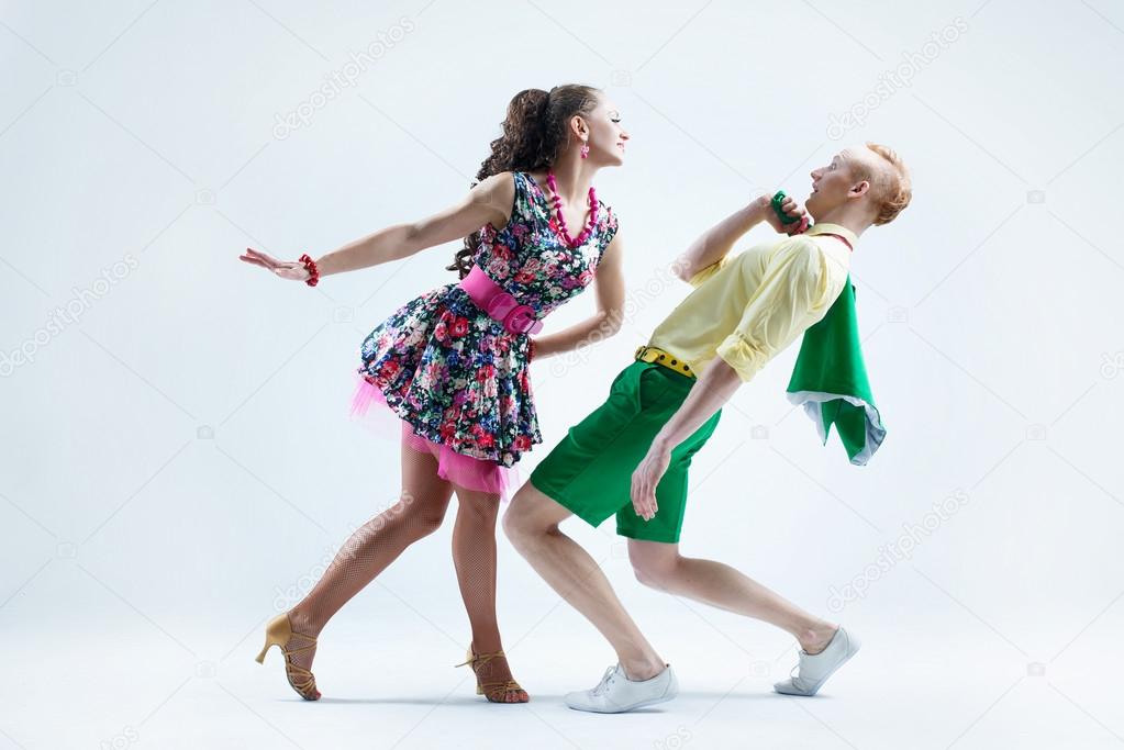 Funny dancer couple dressed in boogie-woogie rock'n'roll pin up style posing together in studio.