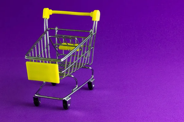 紫色の背景にスーパーマーケットで空のショッピングカート — ストック写真