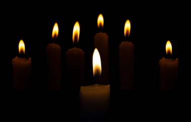 Siyah arka planda karanlıkta mum yakmak. Dini törenlere, bayramlara veya defin törenlerine yanan mumlar eşlik eder.