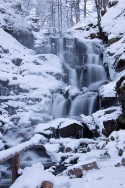 Şelale karla kaplı. Nehir kıyısında kış manzarası