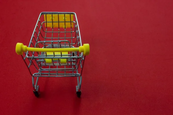 赤い背景にショッピングトロリーのクローズアップ写真 ショッピングにおけるミニマリズム ビジネスコンセプトとオンラインショッピング — ストック写真