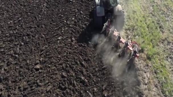 Vista superior de la tierra arada desde un arado arando un tractor en un campo. — Vídeos de Stock