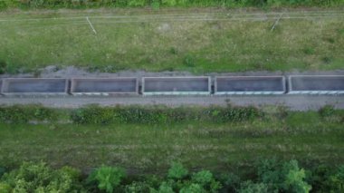 Boş konteynırları taşıyan bir yük treninin hava görüntüsü yeşil otların olduğu bir ormanın içinden geçiyor.