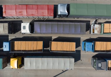 Kargo taşımacılığı. Birçok kamyon limanda boşaltma kuyruğunda bekliyor, tahıl yüklü kamyonlarla bir kuadkopterin üst görüntüsü. Lojistik ve nakliye kavramı.