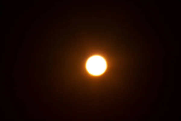 Bright blurred yellow spot. The sun on a black background.