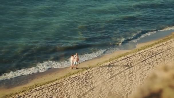 Paar lopen langzaam langs de kust van de koele zee bij dageraad blootsvoets in het water — Stockvideo