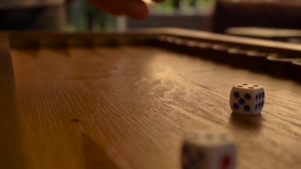 Mano humana masculina suavemente recoge lentamente los dados de tablero de backgammon de madera — Vídeo de stock