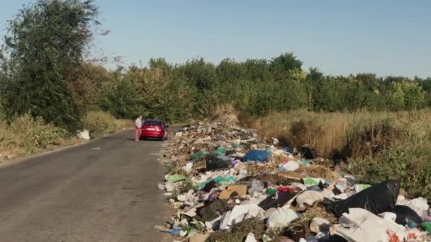 Voitures s'arrêtent juste sur le bord de la route pour jeter leurs ordures dans une décharge spontanée. — Video