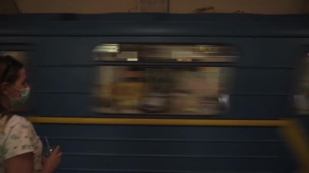 Девушка подходит к краю платформы, садится на прибывающий поезд в метро — стоковое видео