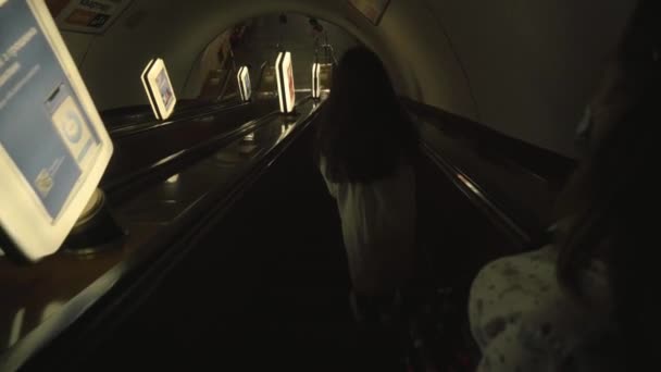 KIEV, UKRAINE - JULY 15, 2021: girls ride empty down escalator. shining bright banners with advertisements — Stock Video
