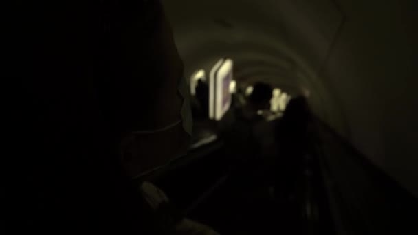 Tıbbi maskeli bir kız, asansörde karanlık bir tünele giriyor. — Stok video